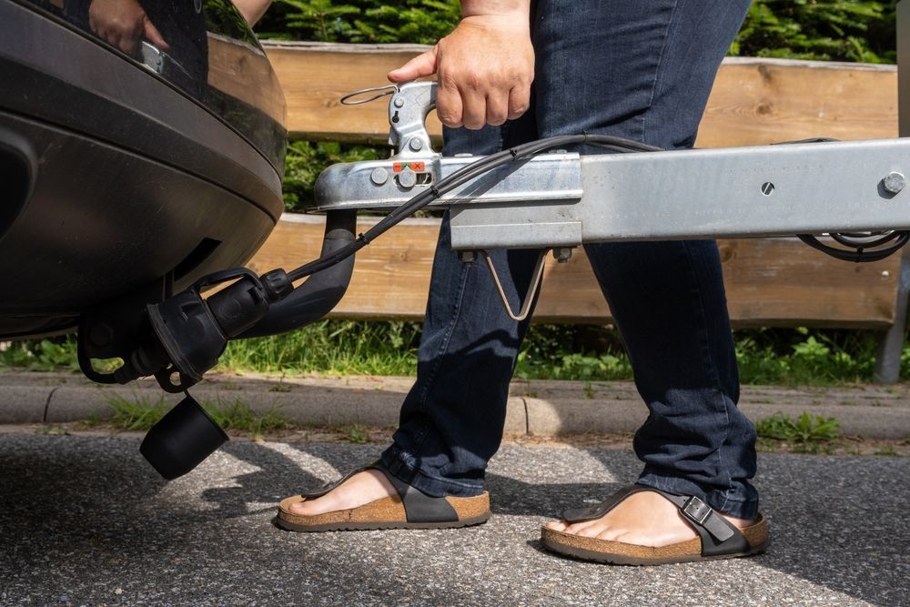 A person is attaching a trailer to the back of a car - Whitsunday 4x4 & Automotive In Cannonvale, QLD