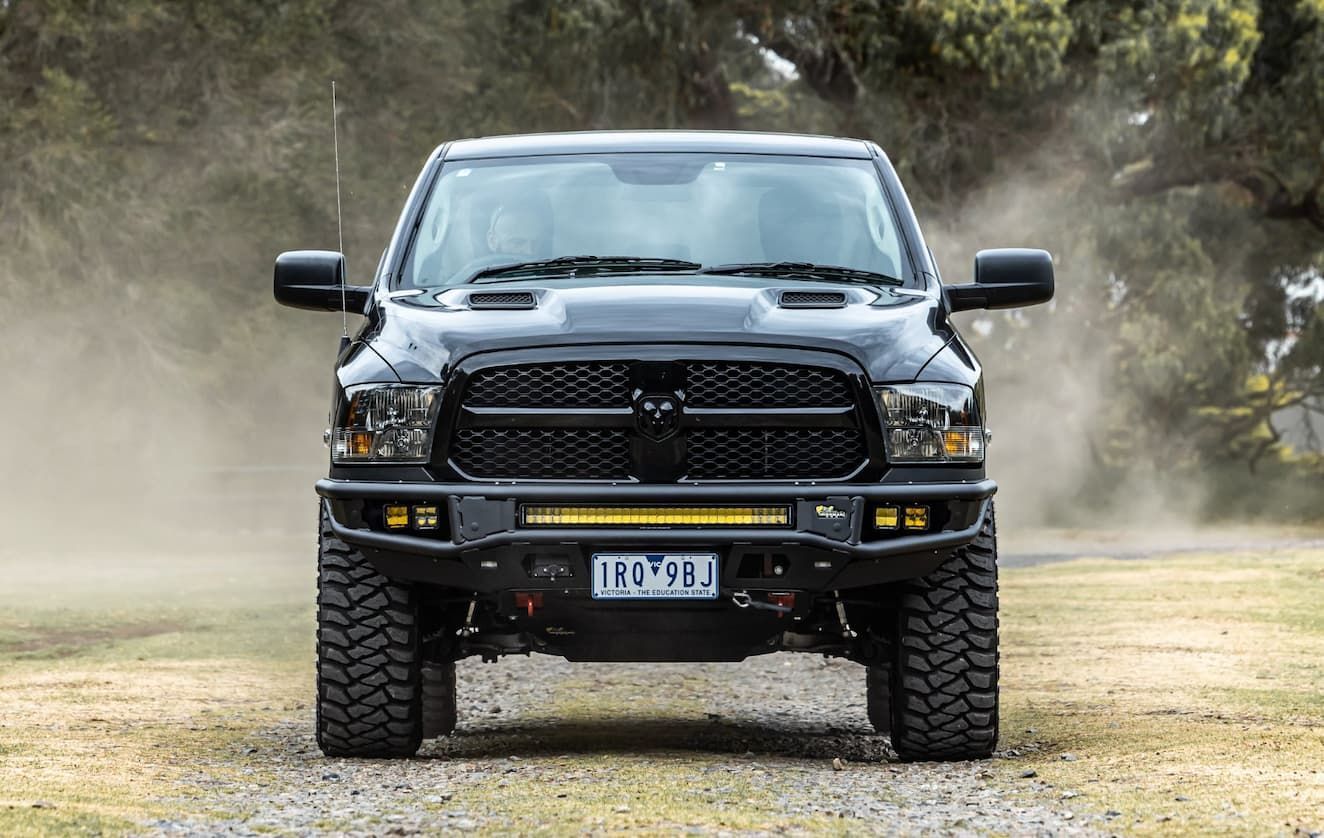 A Black Truck is Driving Down a Dirt Road — Whitsunday 4x4 & Automotive In Cannonvale, QLD