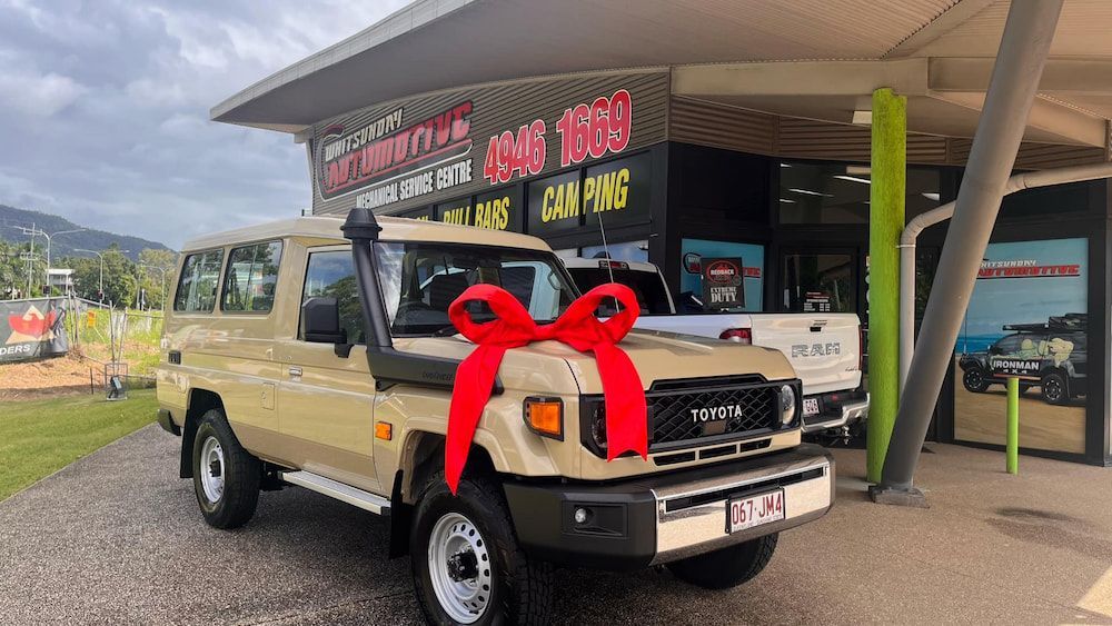 A Car With a Red Bow on It is Parked in Front of a Building — Whitsunday 4x4 & Automotive In Cannonvale, QLD