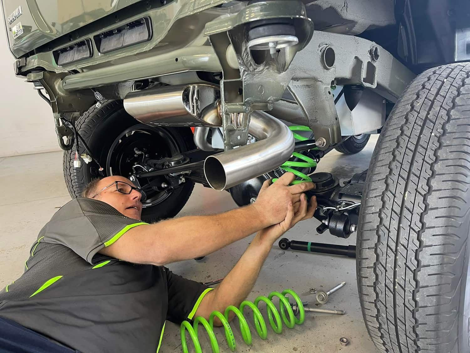 A Man is Working on the Underside of a Car — Whitsunday 4x4 & Automotive In Bowen, QLD