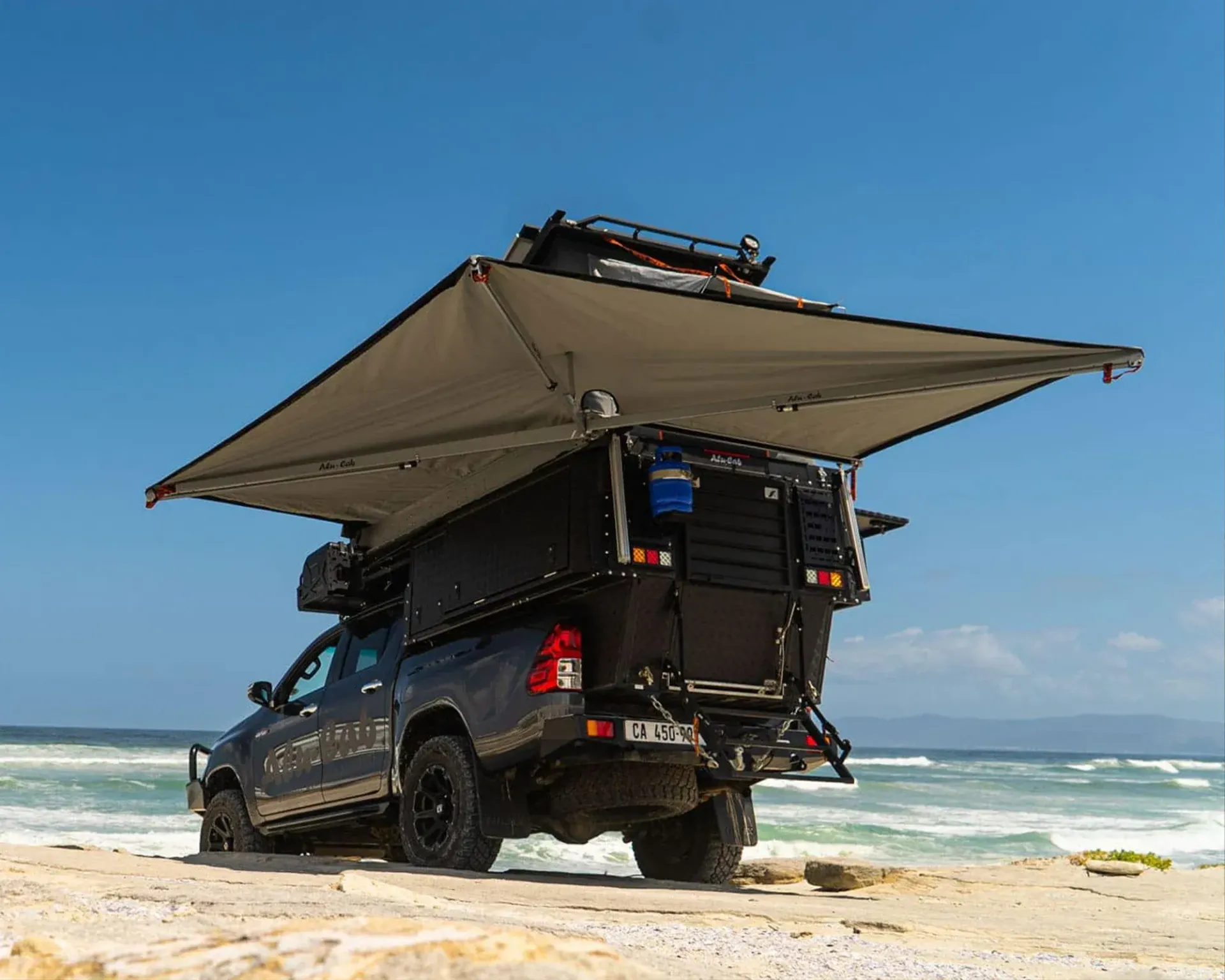 Off-road SUV with rooftop tent and awning parked on a sandy beach by the ocean — Whitsunday 4x4 & Automotive In Proserpine, QLD