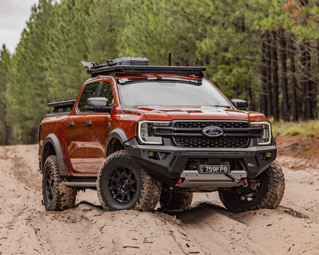 A Red Truck with a Roof Rack is Driving Down a Dirt Road - Whitsunday 4x4 & Automotive In Cannonvale, QLD