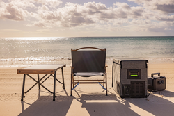 A chair , table , and cooler are on the beach near the ocean - Whitsunday 4x4 & Automotive In Cannonvale, QLD