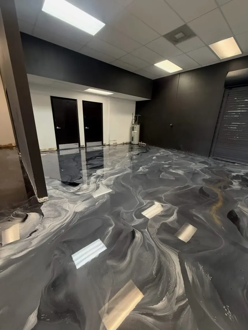Empty room with gray marbled floor, black walls, and ceiling lights reflecting on the glossy surface