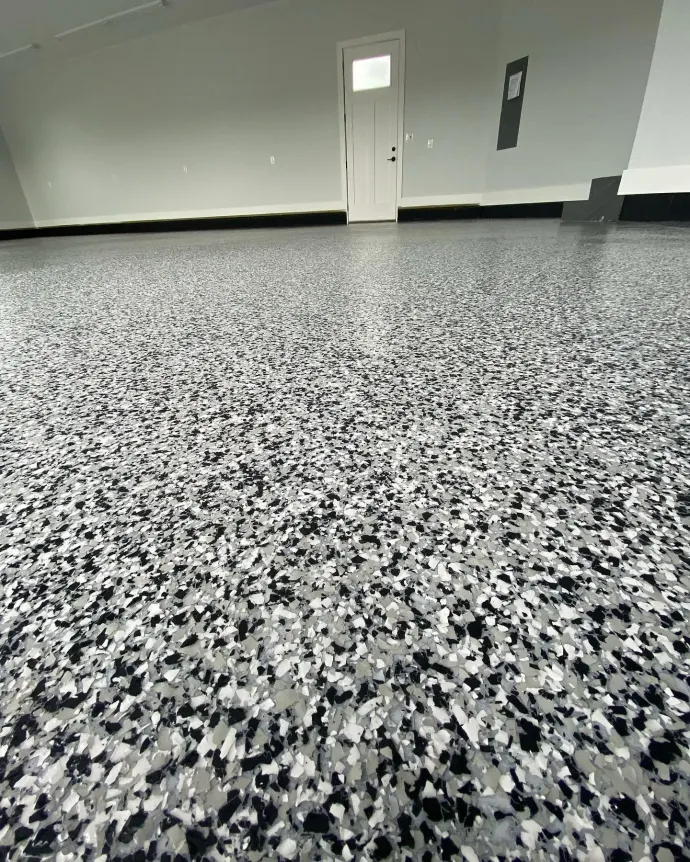 Empty room with speckled gray epoxy floor and a plain door on the far wall.