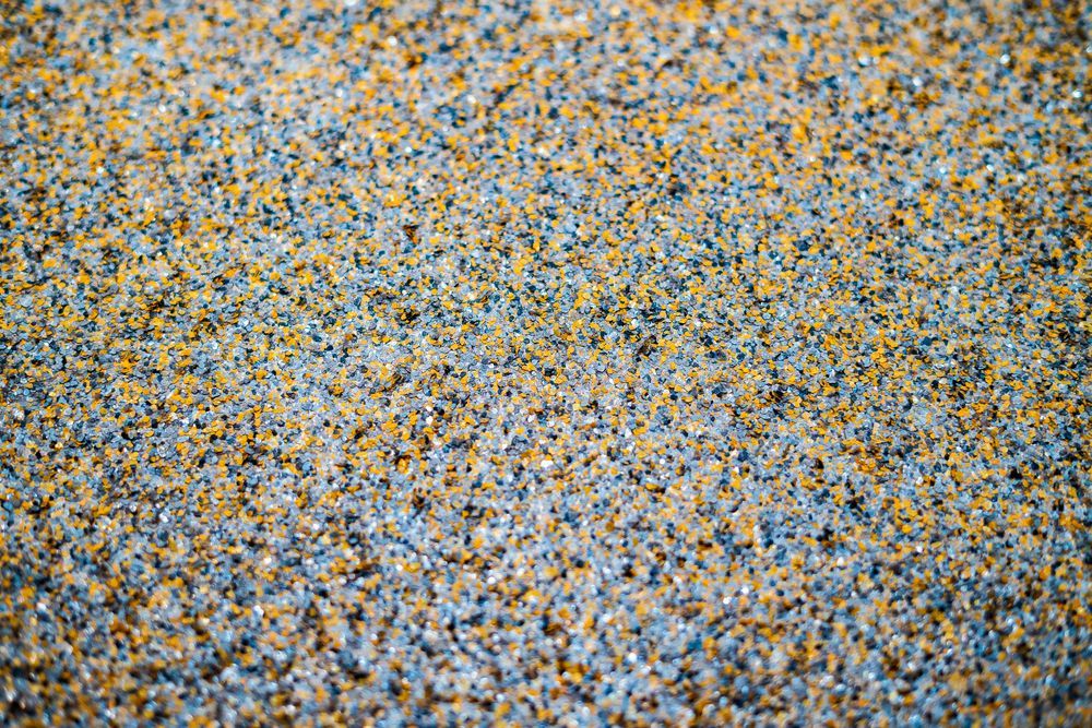 Close-up of a speckled gray, blue, and yellow pebble or gravel surface