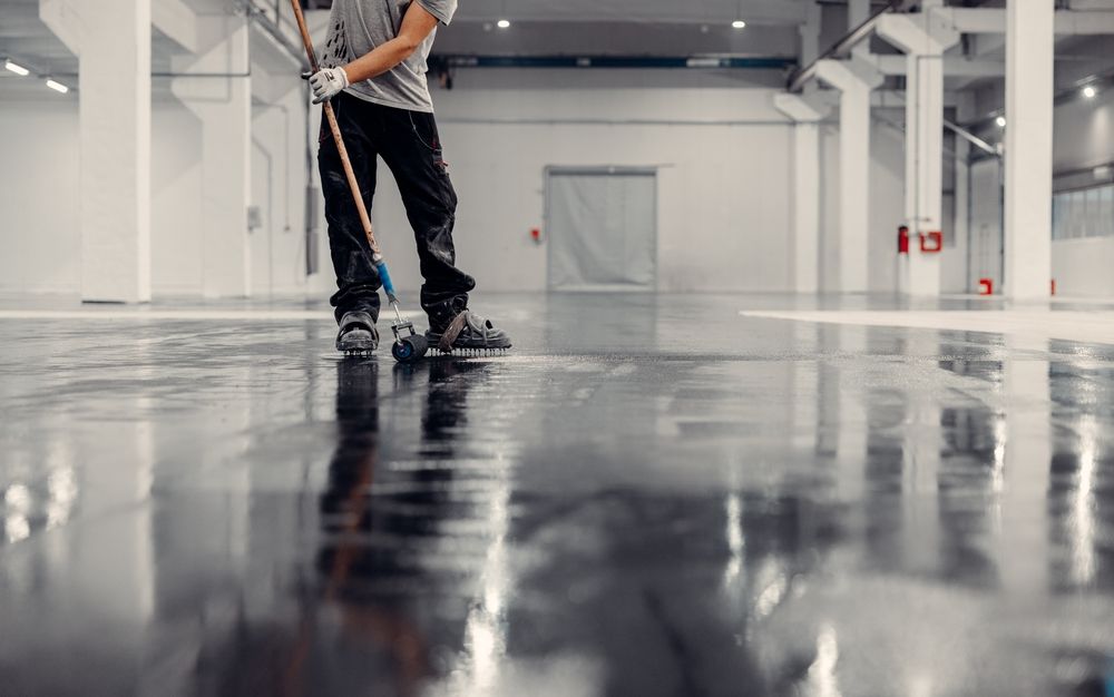 Person mopping a glossy floor in a bright, empty indoor space