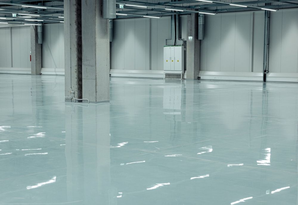 Empty industrial warehouse with glossy light-blue floor and metal support columns