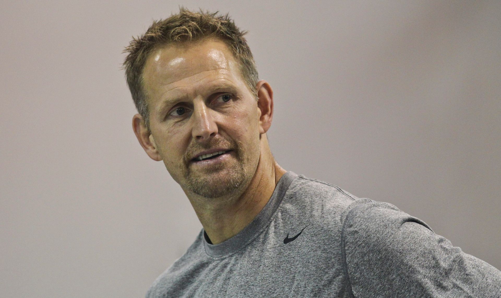 Man in a gray shirt looking off to the side against a plain wall
