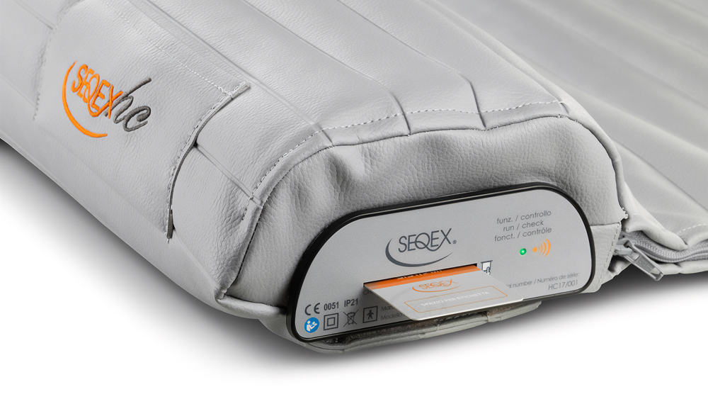 Gray portable medical cushion with an electronic control panel and orange logo on the side
