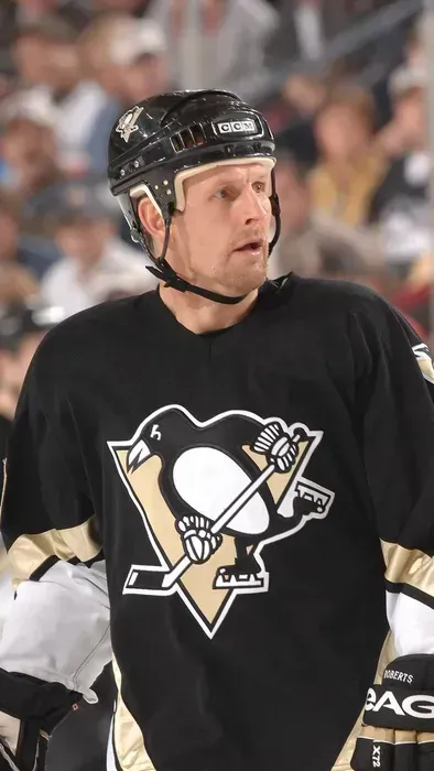 Hockey player in black Pittsburgh Penguins jersey and helmet looking to the side on the ice