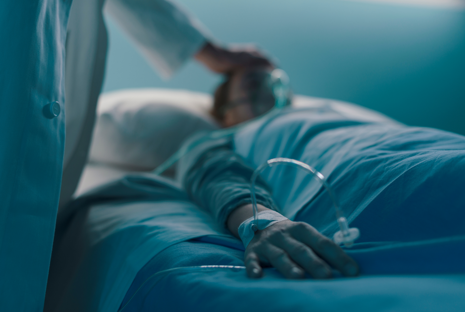 A person is laying in a hospital bed with an iv in their arm.
