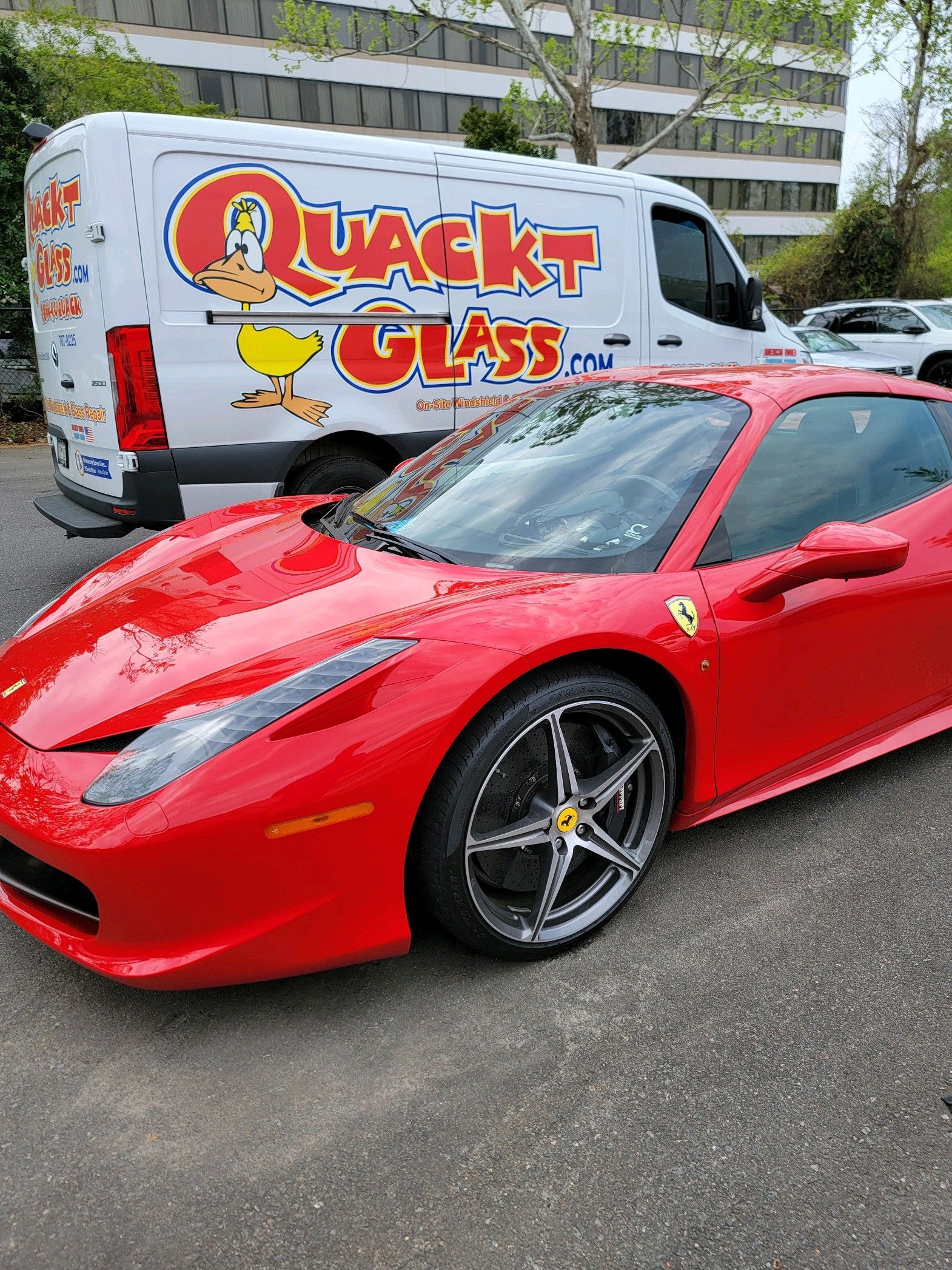 Red Ferrari parked next to a white service van labeled 