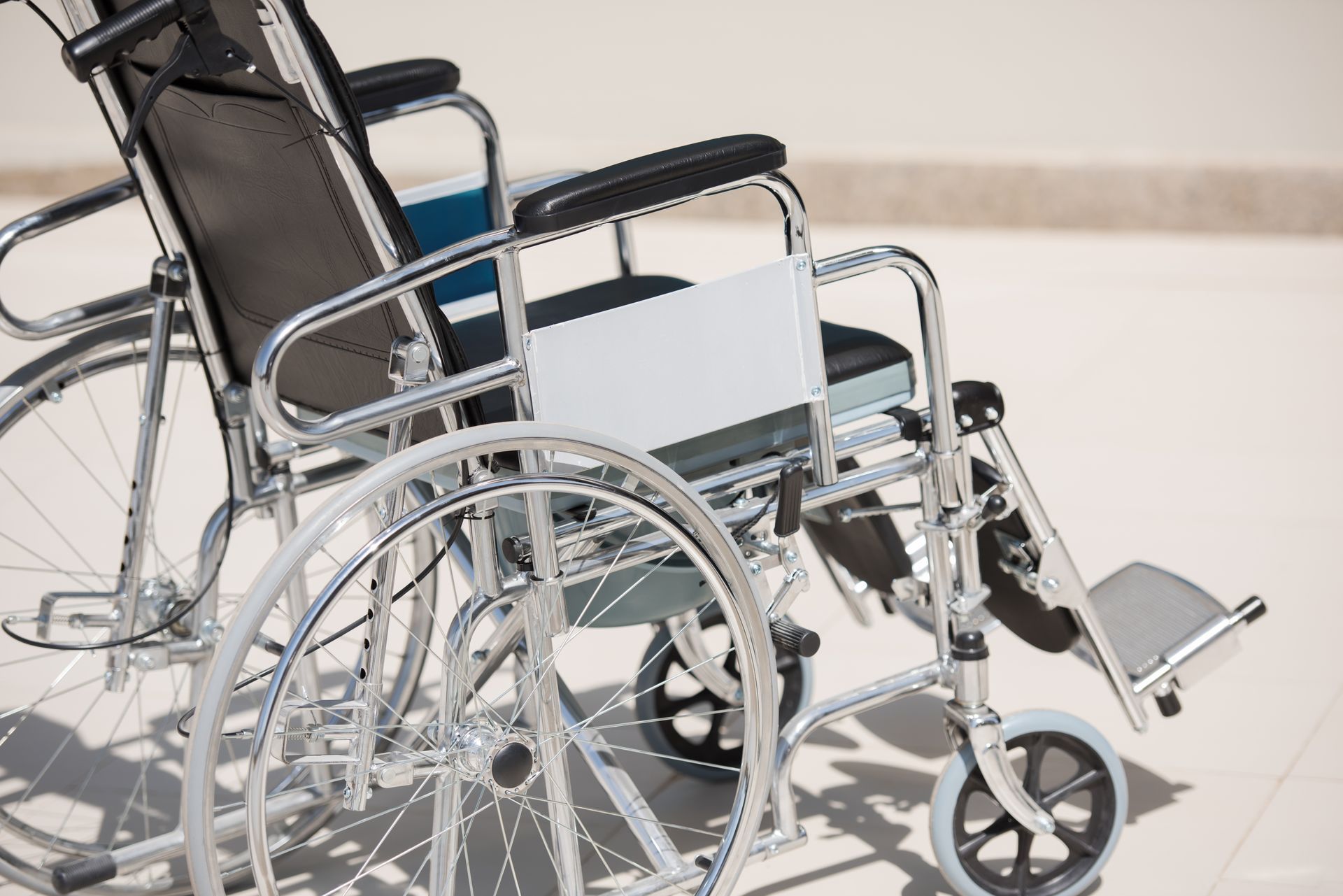 Manual wheelchair with metal frame, large rear wheels, and footrests for mobility support.