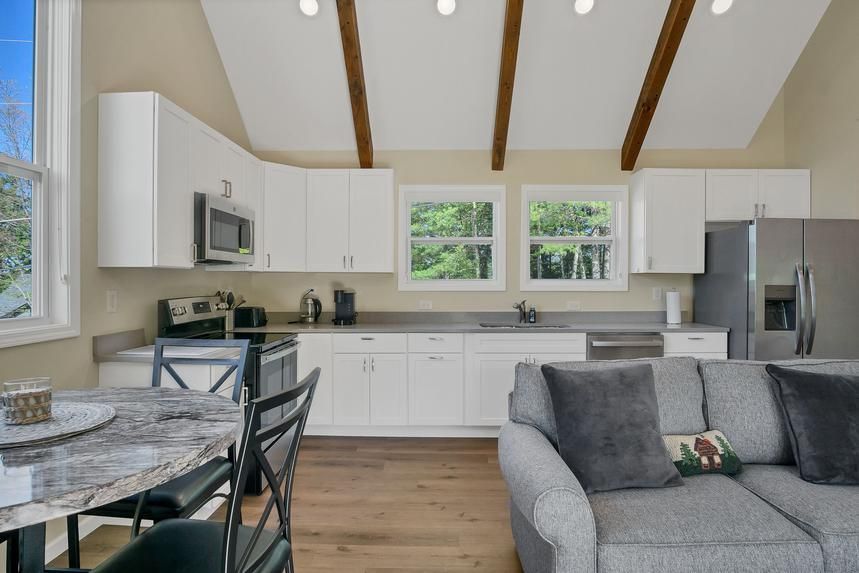 A living room with a couch , table , chairs and a kitchen.