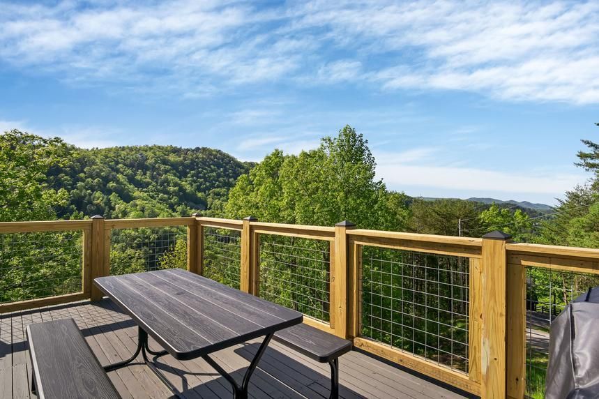 There is a picnic table on the deck with a view of the mountains.