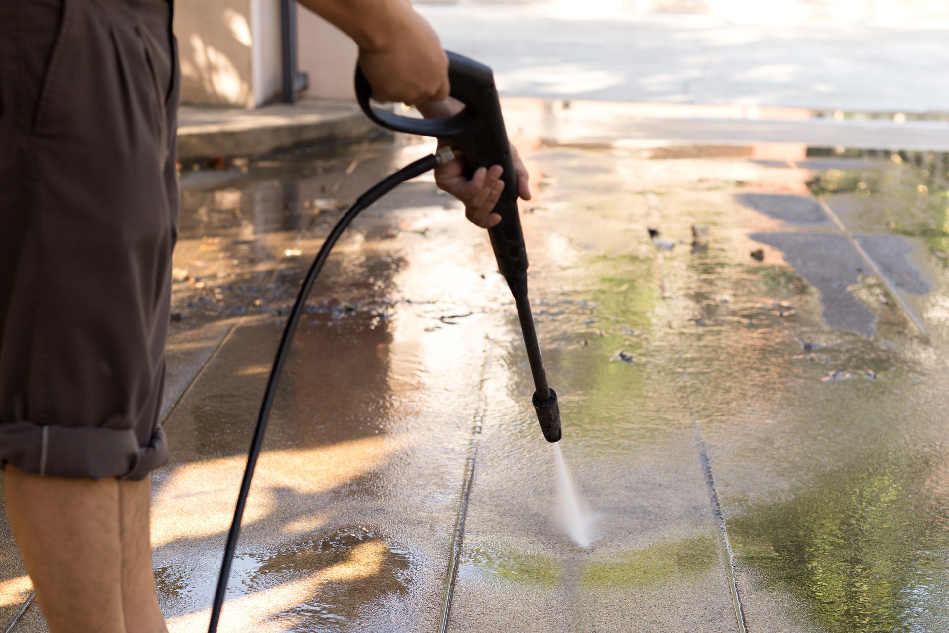 A power washer washes green algae off of a walk way - amazing finish windows, tx