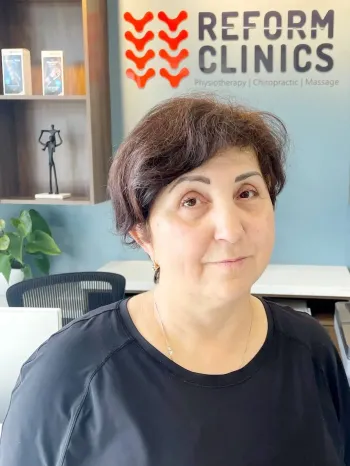 Woman seated in a clinic lobby beneath a Reform Clinics sign