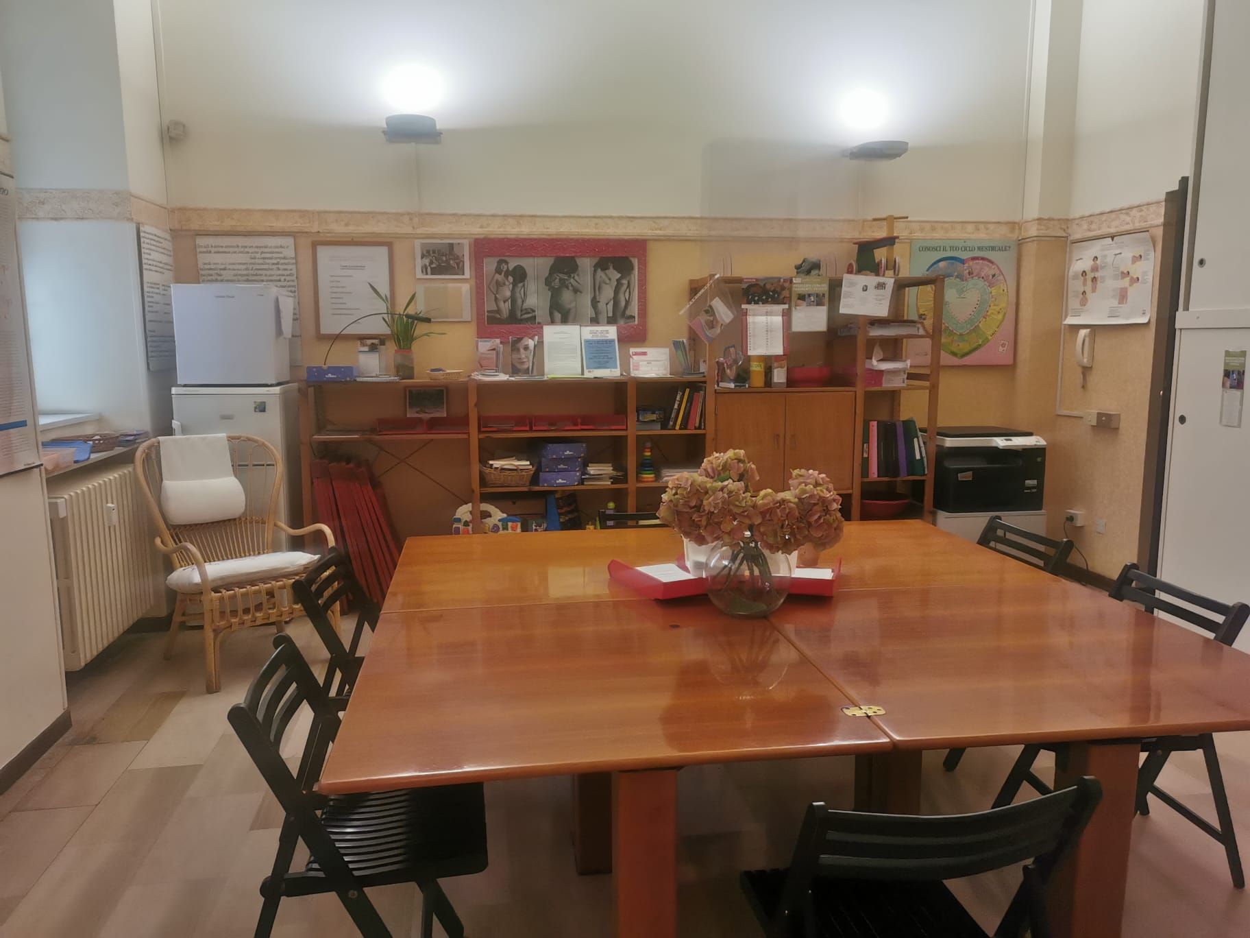 Sala da pranzo con tavolo in legno, sedie e scaffali contro il muro.