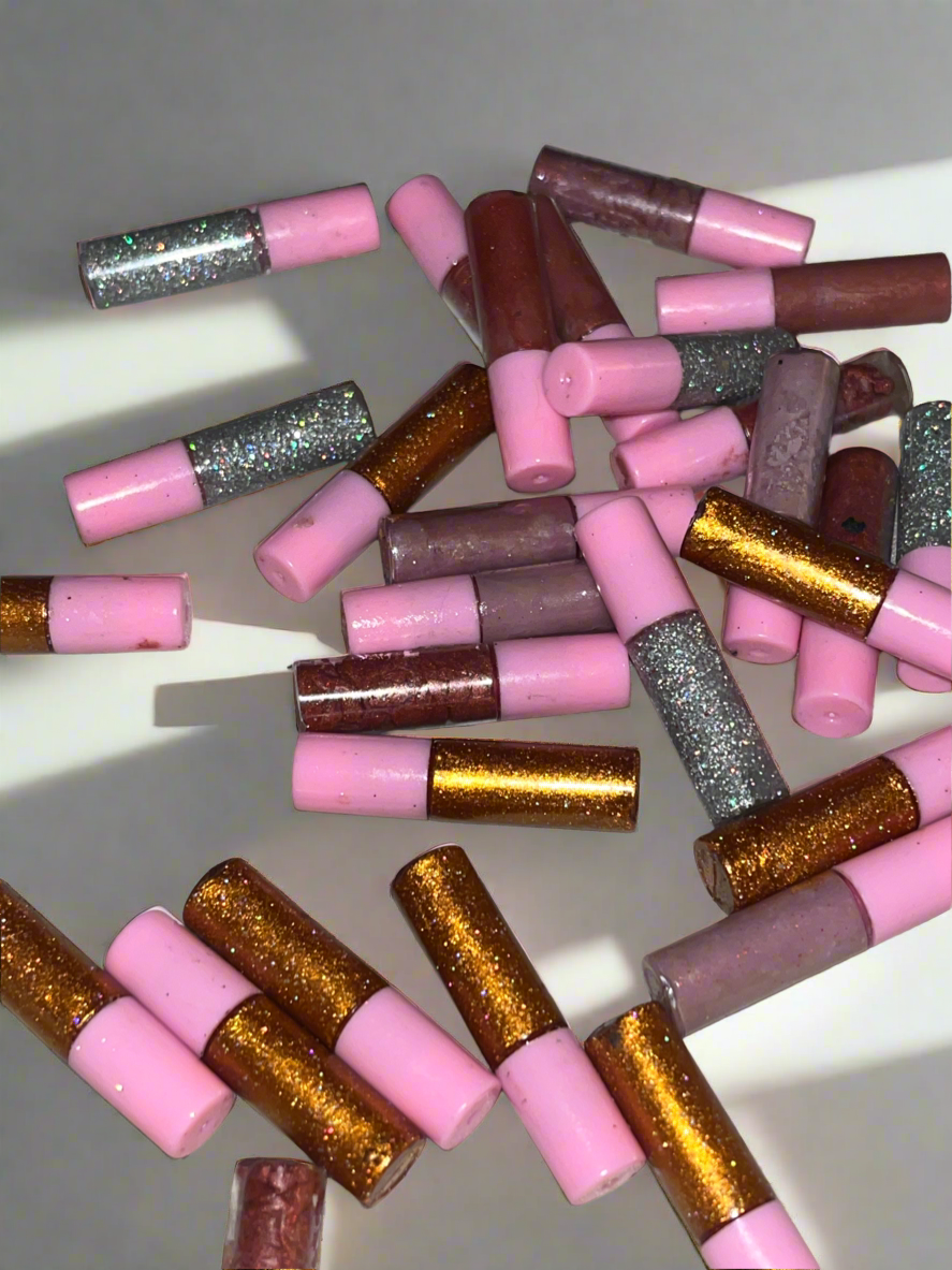 Scattered pink, silver, and gold glittery cylindrical pieces on a white surface