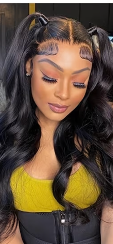 Woman with long wavy black hair, yellow top, and black corset, looking down with makeup and twin ponytails