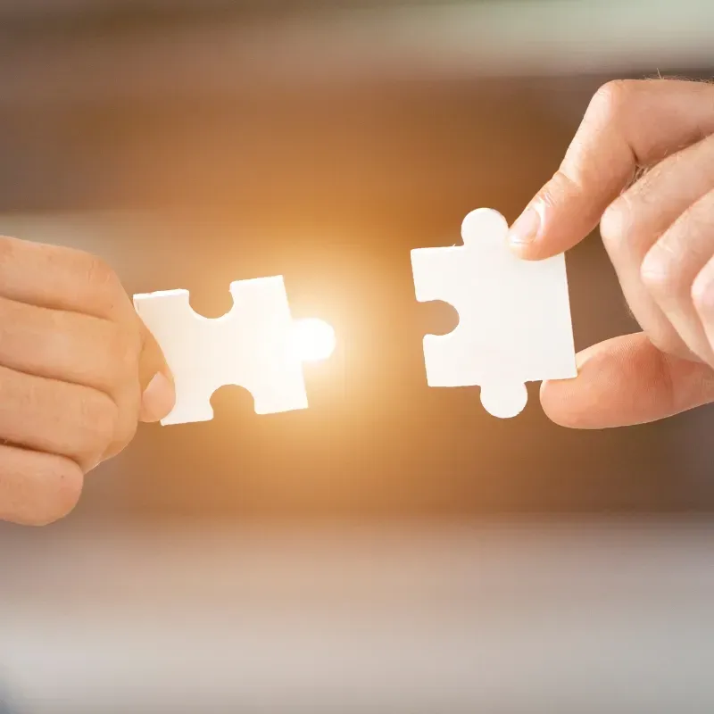 Two people are connecting two puzzle pieces together.