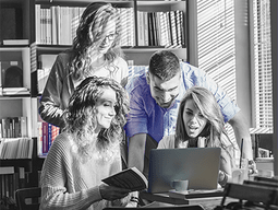 A group of people are looking at a laptop computer in a library.