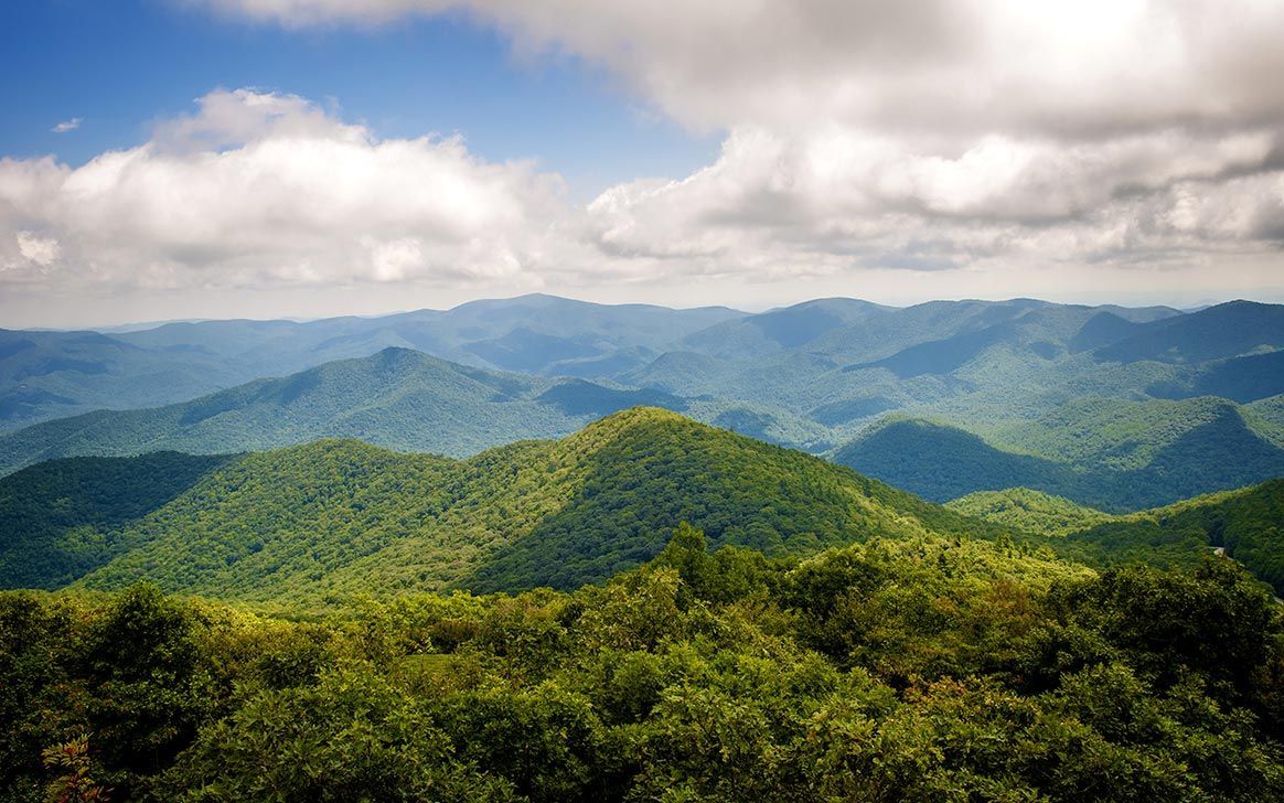 A view of a mountain range with trees on the hills
