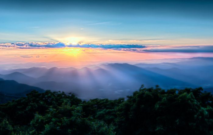 The sun is shining through the clouds over the mountains.