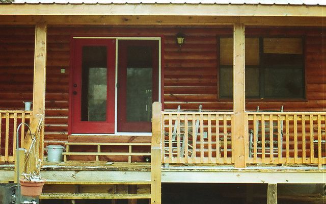 A log cabin with a porch and a red door