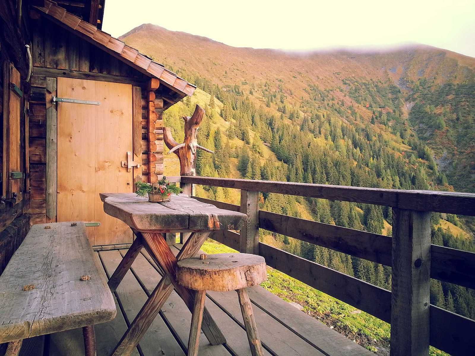 A wooden deck with a table and chairs overlooking a mountain range