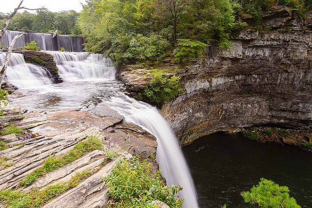 A waterfall is surrounded by trees and rocks in the middle of a forest.