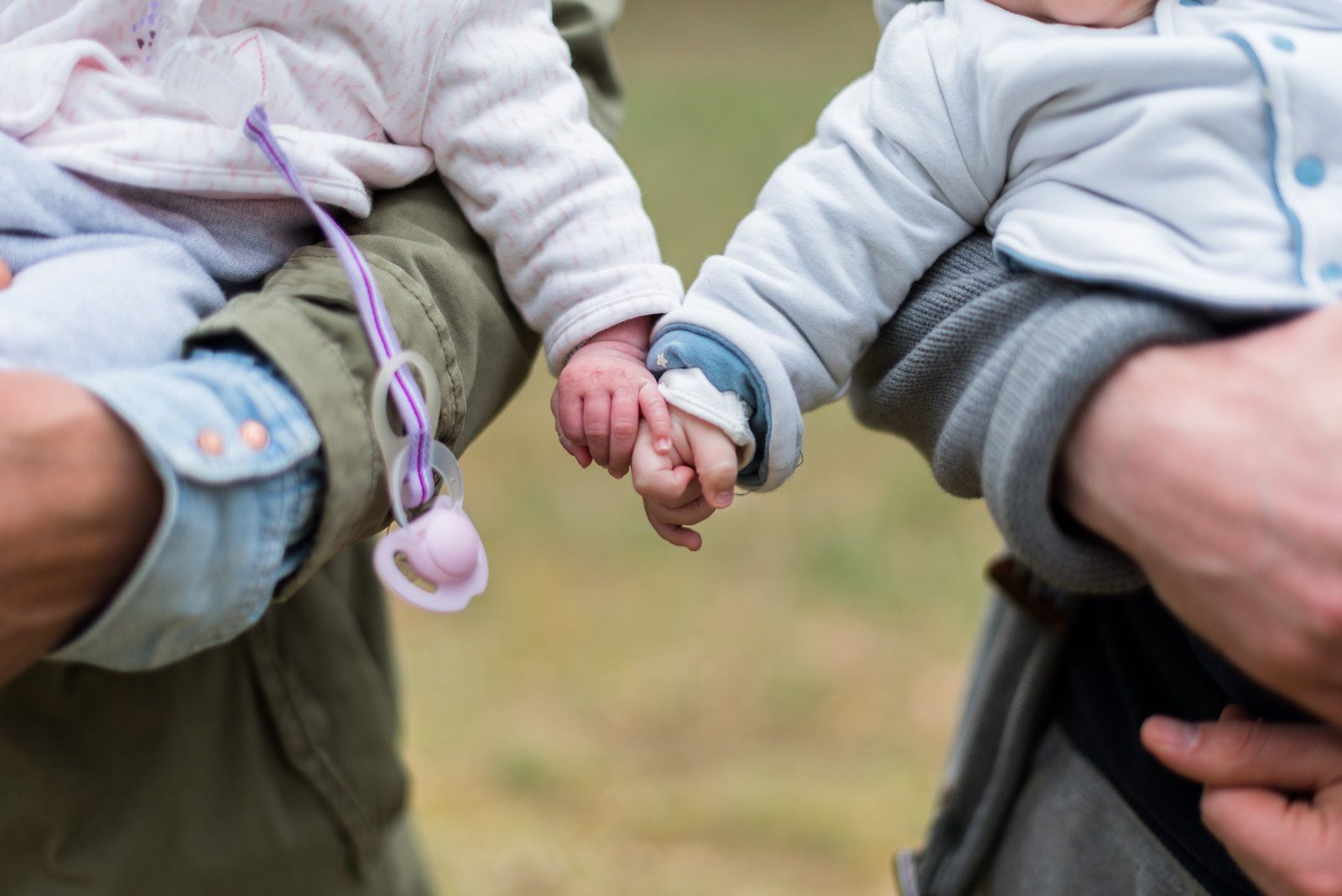 A man is holding two babies in his arms and they are holding hands