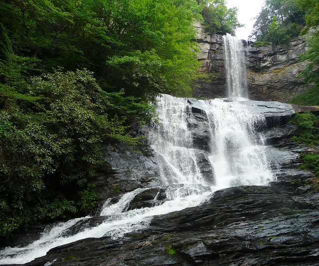 A waterfall is surrounded by trees and rocks in the woods