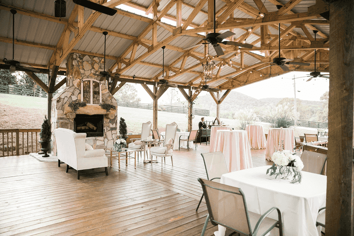 A wooden pavilion with tables and chairs and a fireplace