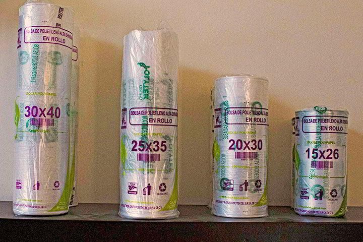Rollos de bolsas de plástico de diferentes tamaños están alineados en un estante.
