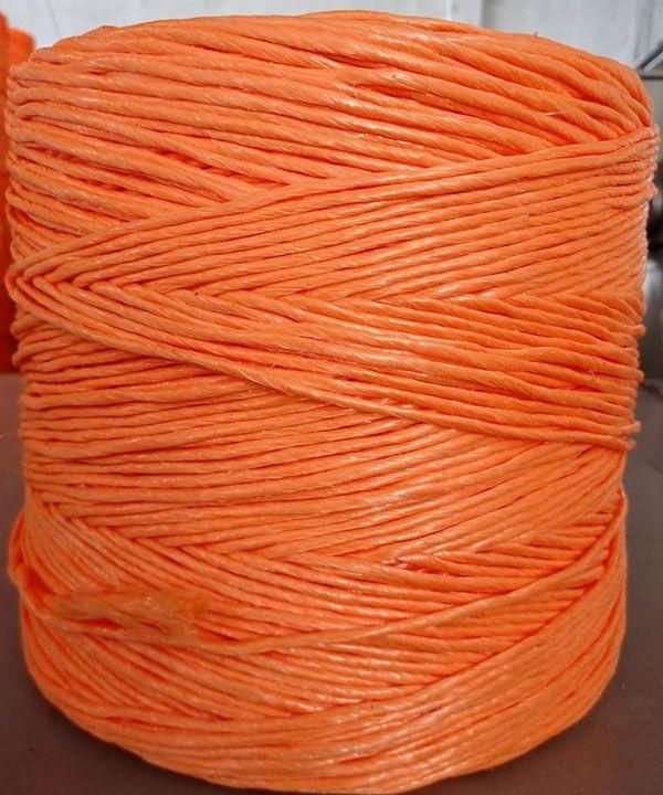 Un carrete de hilo naranja está sobre una mesa.