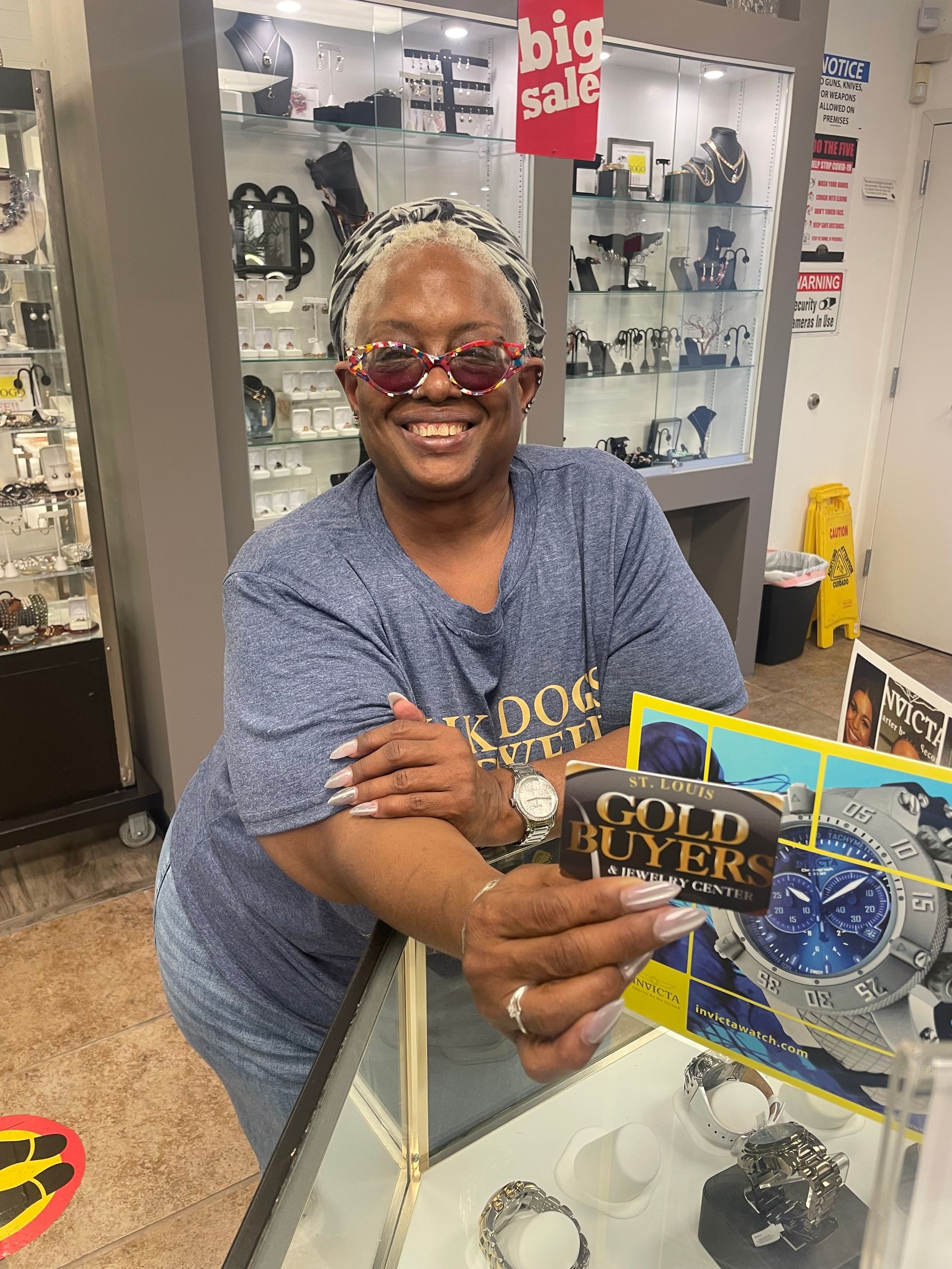 A woman is standing in a jewelry store holding a watch and a card.