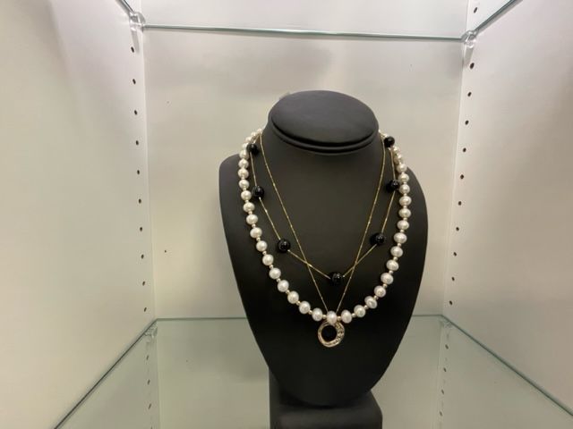 A necklace on a mannequin in a glass case