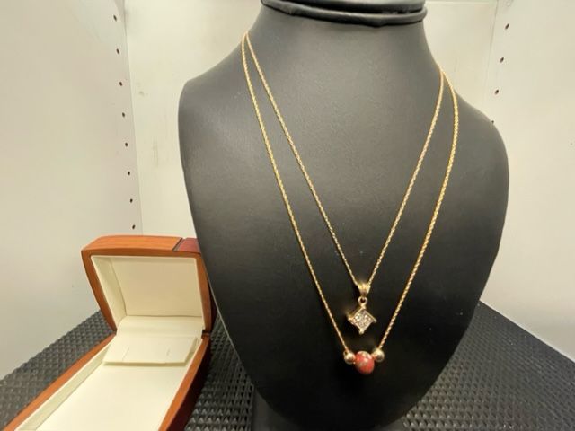 A necklace is on a mannequin next to a box