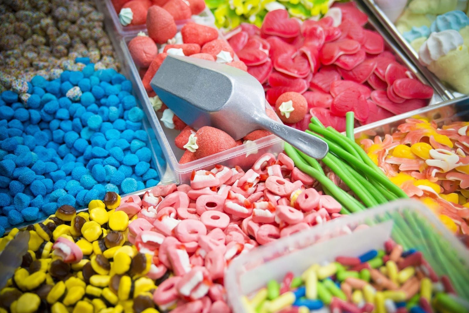 Présentoir de confiserie avec une variété de bonbons colorés : bleus, jaunes, roses, rouges et verts.