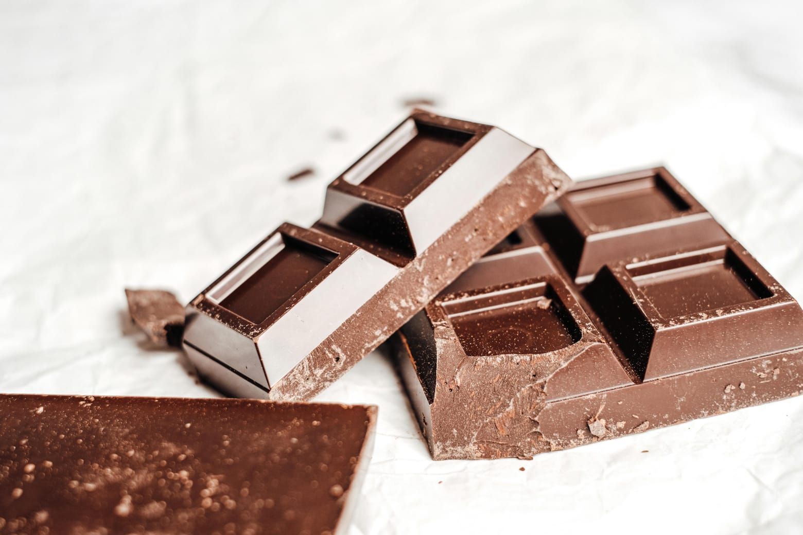Une planche à découper en bois garnie de carreaux de chocolat et de grains de café.