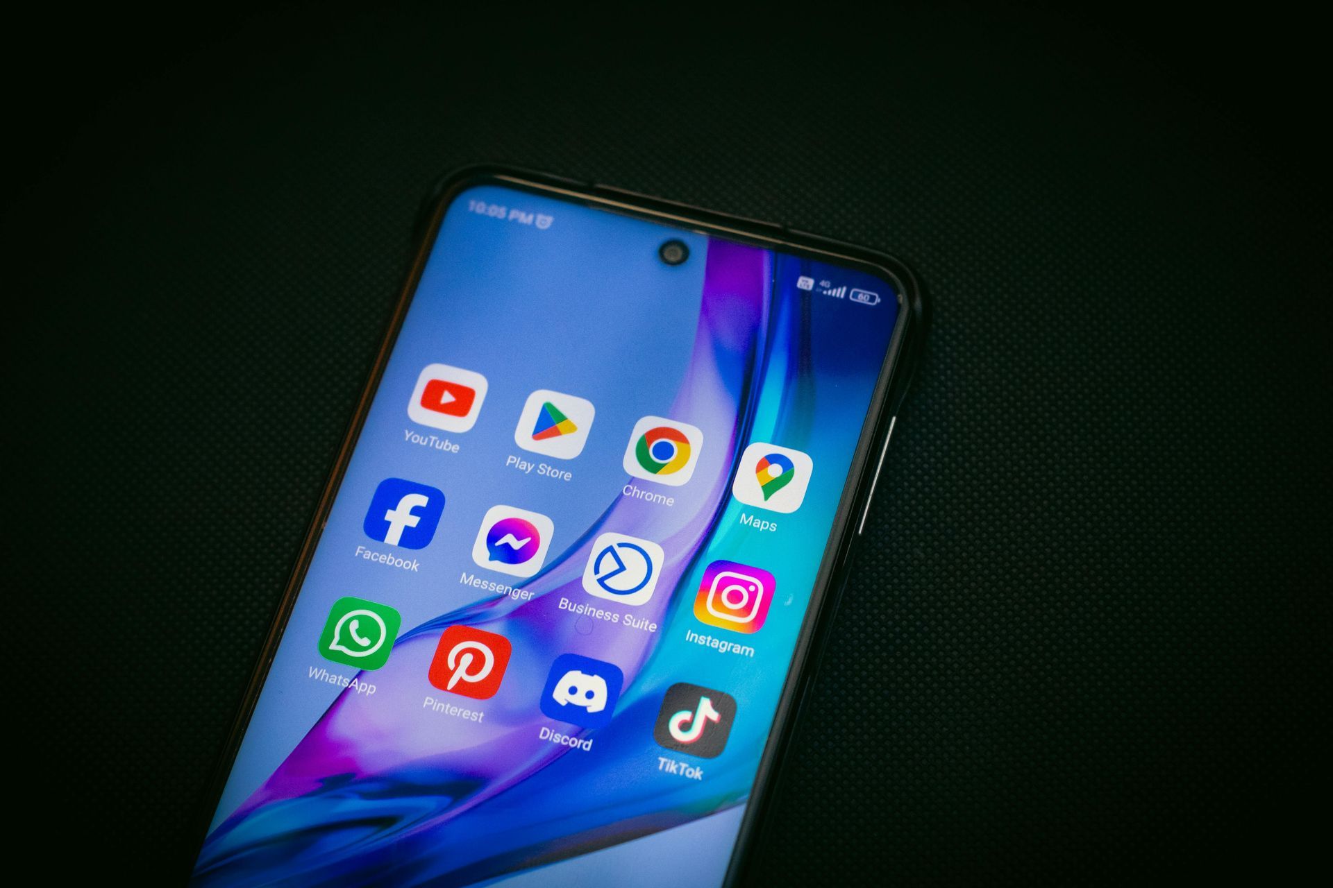 Un écran de smartphone affichant des icônes d'applications sur un fond d'écran bleu-violet coloré.