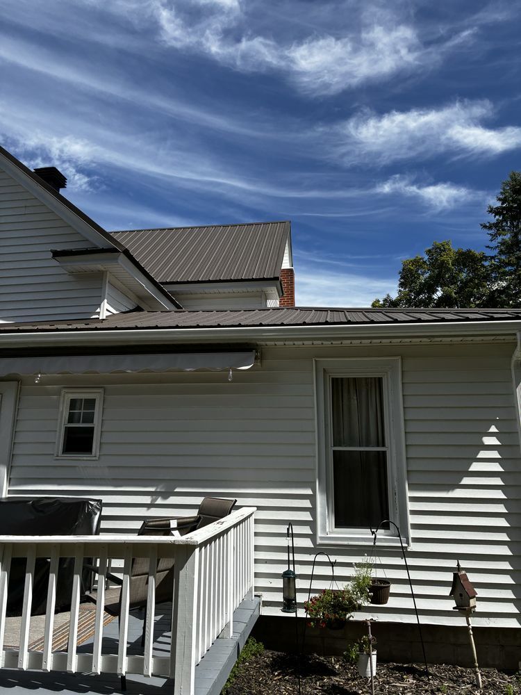 White house siding and porch railing under a partly cloudy blue sky.