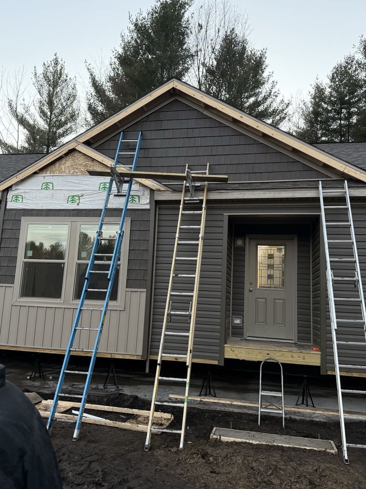House exterior under construction with multiple ladders leaning against the front facade