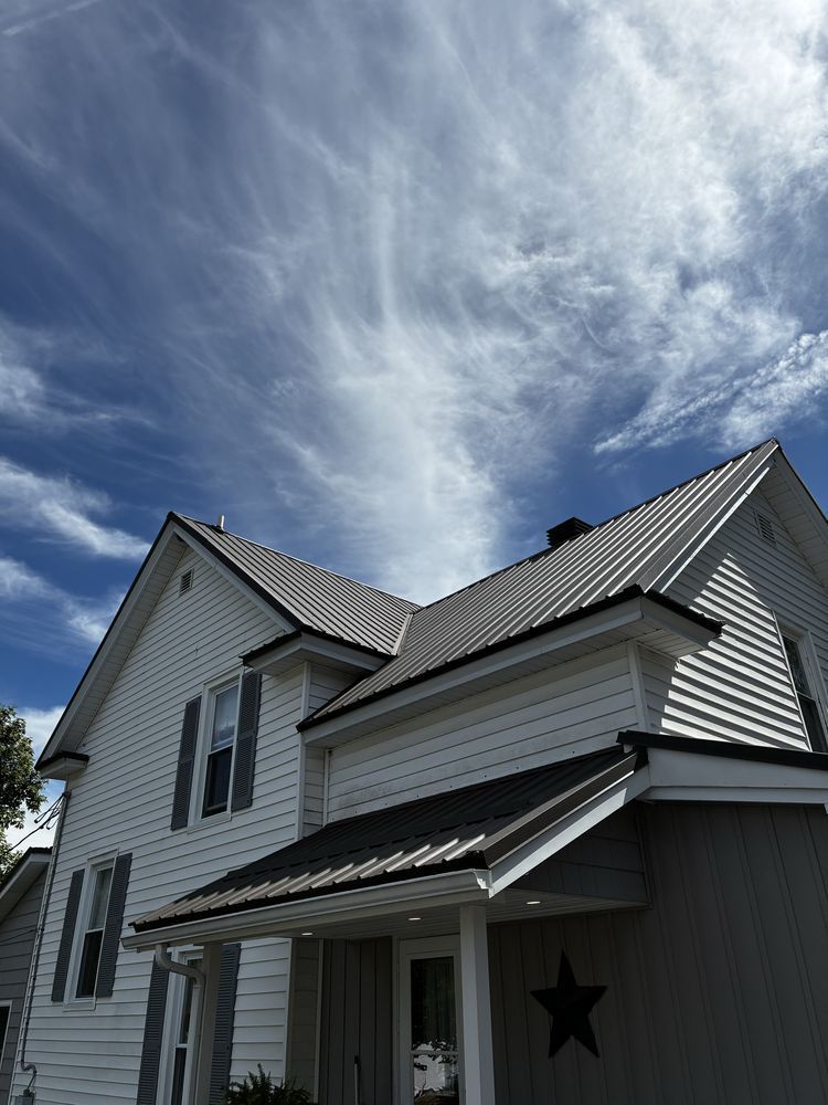 White house with gray metal roof under a dramatic cloudy blue sky