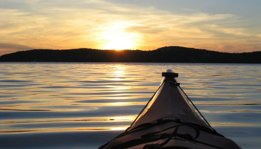 A kayak is floating on a lake at sunset
