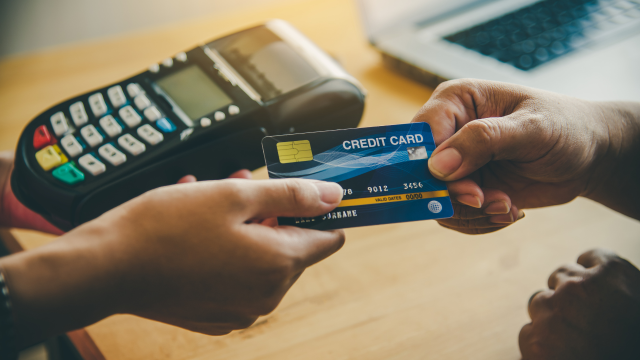 A person is holding a credit card in front of a credit card machine.