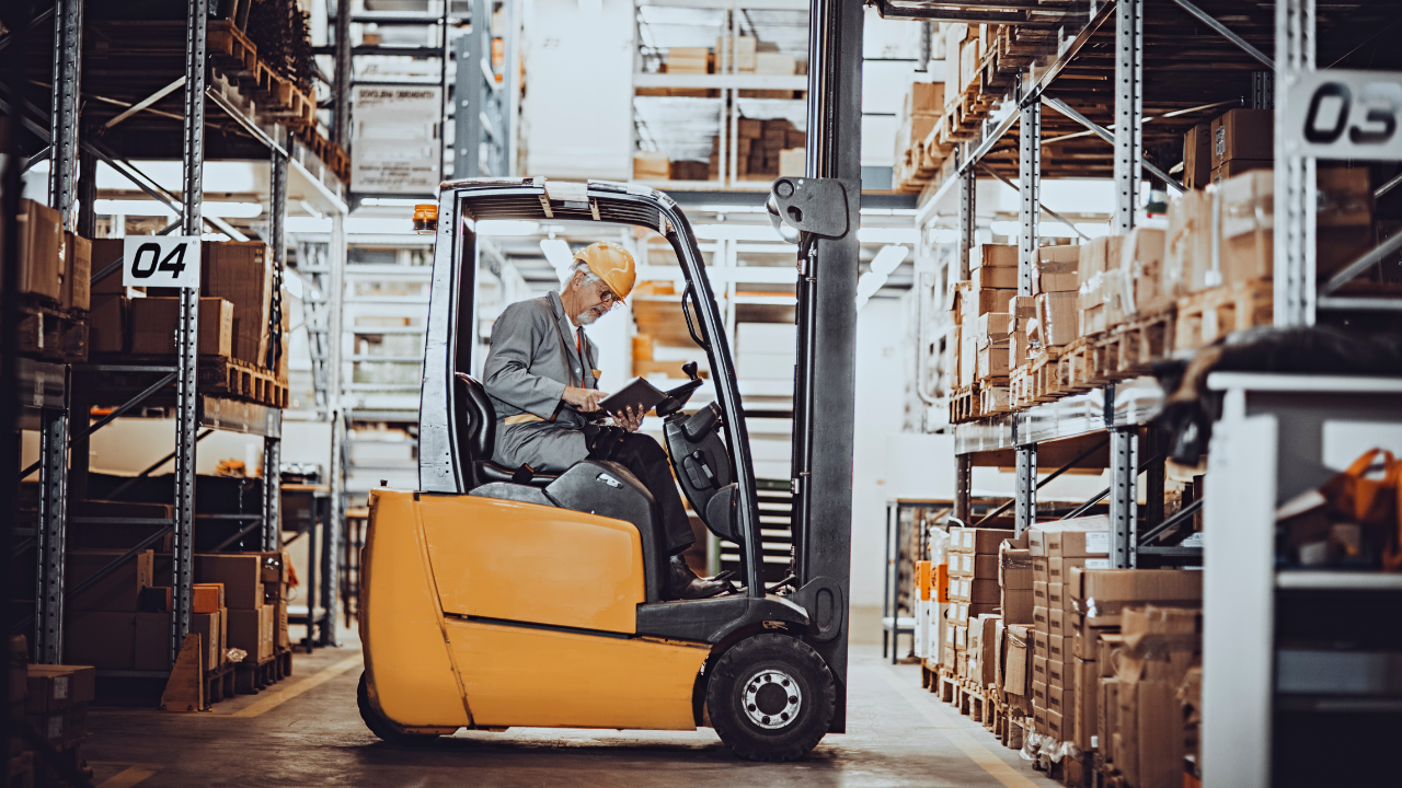 A man is driving a forklift in a warehouse.