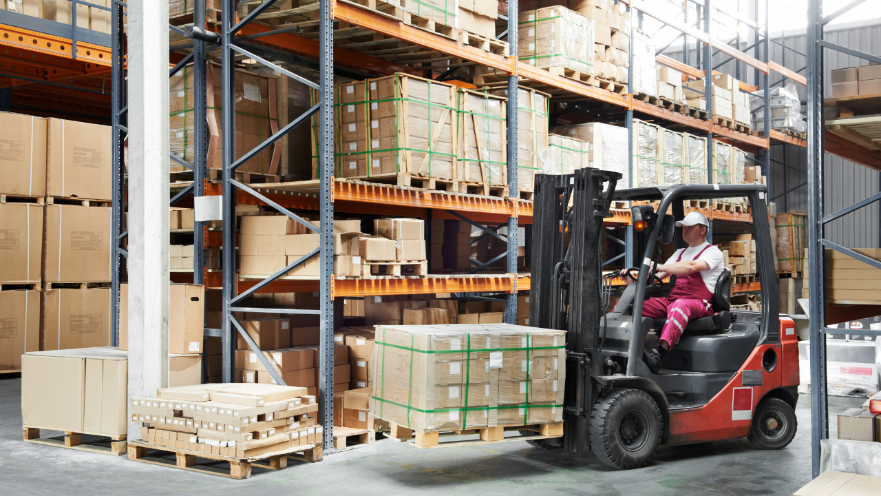 A man is driving a forklift in a warehouse.